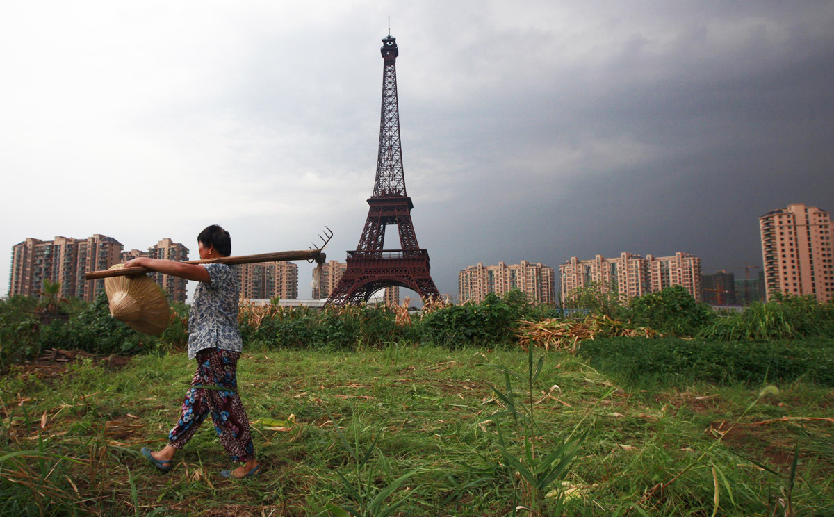 A farmer walks past a replica of the Eiffel Tower at the Tianducheng development in Hangzhou, Zhejiang Province. Tianducheng, developed by Zhejiang Guangsha Co. Ltd., started construction in 2007 and was known as a knockoff of Paris.