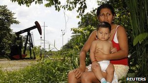 Maria Eugenia Briceno and her son sit in front of her house which is just in front of an oil well in Lago Agrio, Ecuador, January 2011