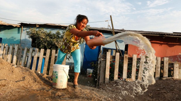 CHANGING TIMES: Betty Guerrero throws dirty water which was used for laundry, outside her home on the outskirts of Lima. Water will become scarcer in sprawling settlements such as Nuevo Pachacutec on the Pacific coast as the population of Peru's capital surges and global warming thaws Andean glaciers, reducing flows in coming decades as the ice disappears.